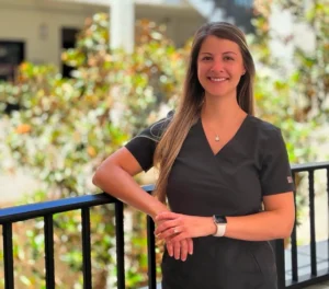 Smiling woman in scrubs leaning on railing